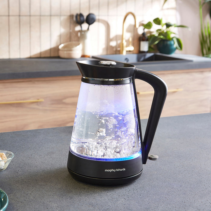 Glass kettle with black handle on a kitchen counter
