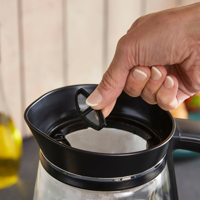 Hand adjusting a filter in a kettle with a blurred background