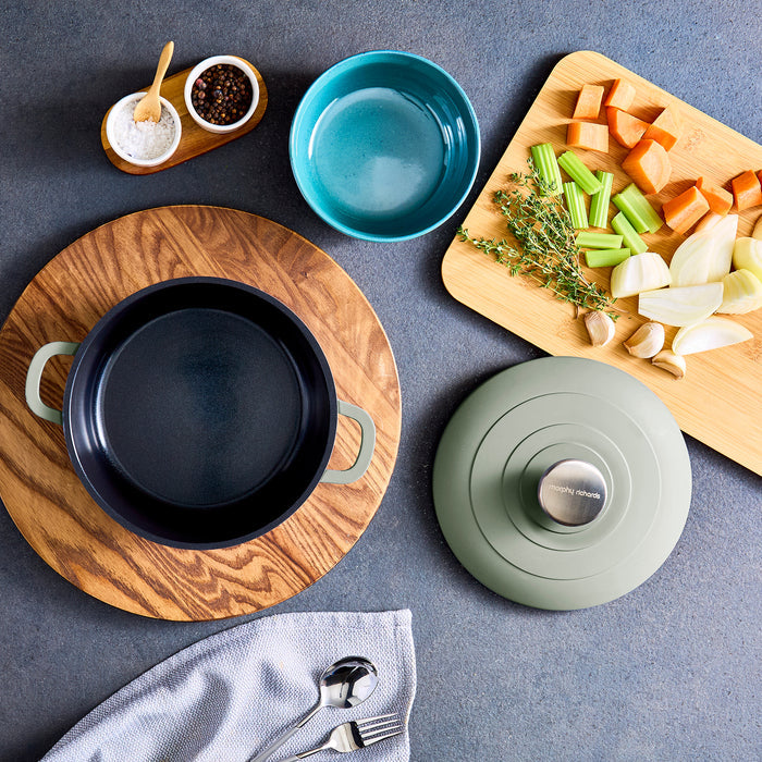 Culinary setup with cookware, cutting board, and ingredients on a grey surface