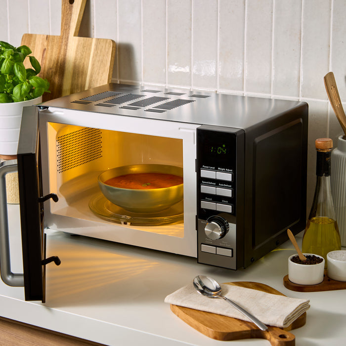 Microwave oven with a bowl of soup inside on a kitchen counter.