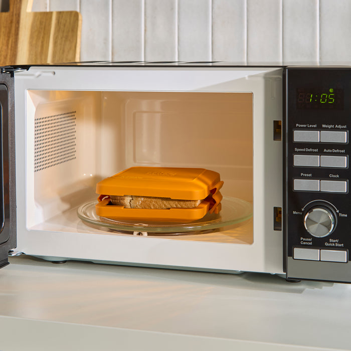 Cheese sandwich inside a microwave oven on a kitchen counter.