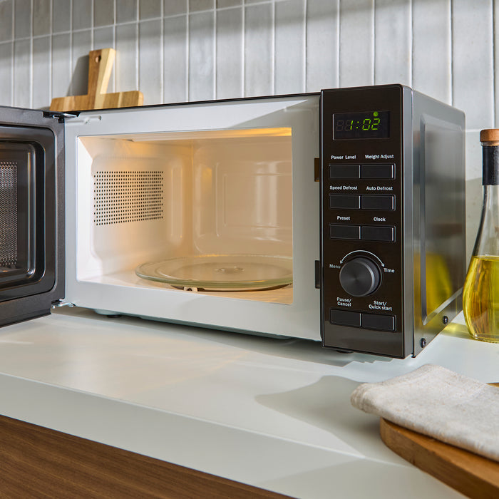Microwave oven on a kitchen counter with a tiled backsplash