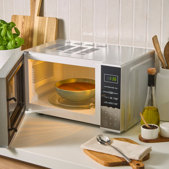Microwave oven with a bowl of soup inside on a kitchen counter.