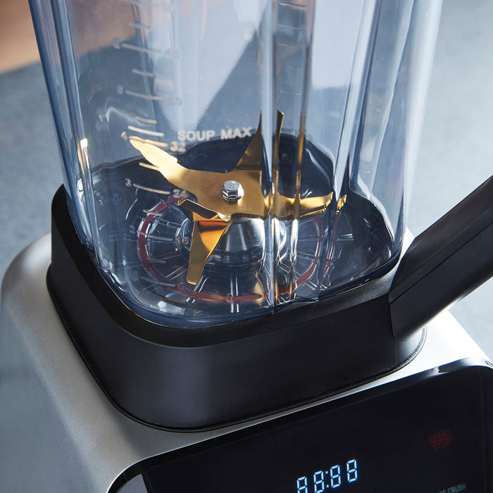 Blender with clear container and gold blades on a gray surface