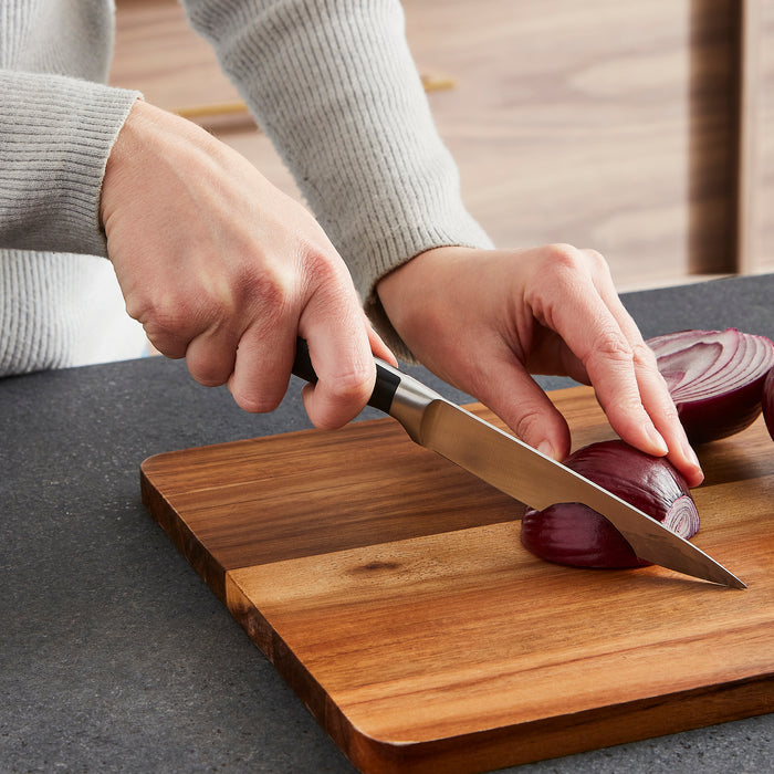 Person cutting an onion on a wooden cutting board with a knife.