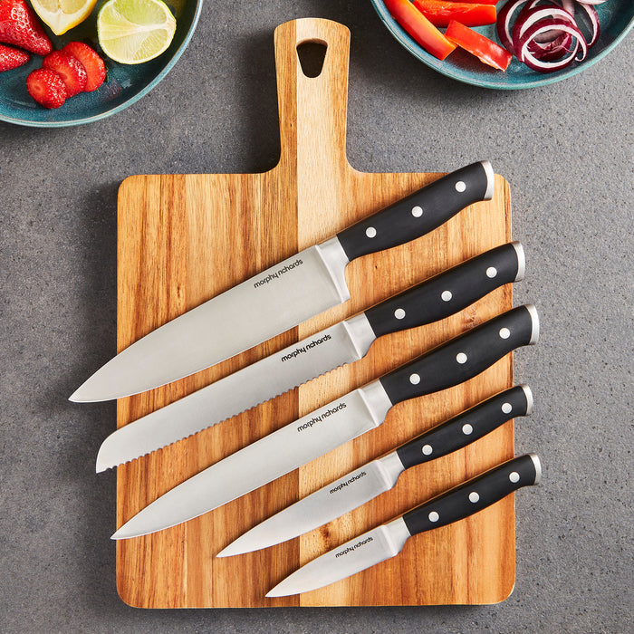 Set of knives on a wooden cutting board with a gray background