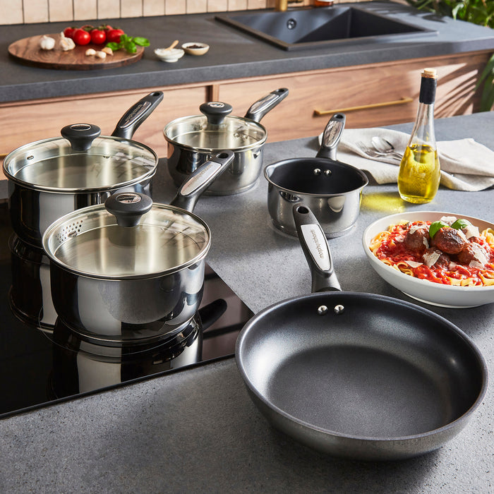 Set of cookware on a kitchen counter with a pan and pots.