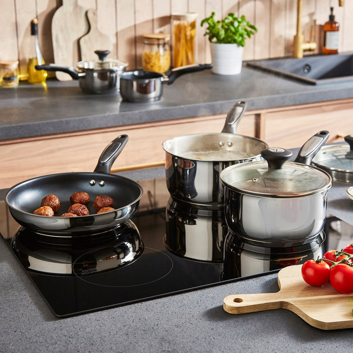 Kitchen scene with cookware on a stove, including pots, pans, and a frying pan with food.