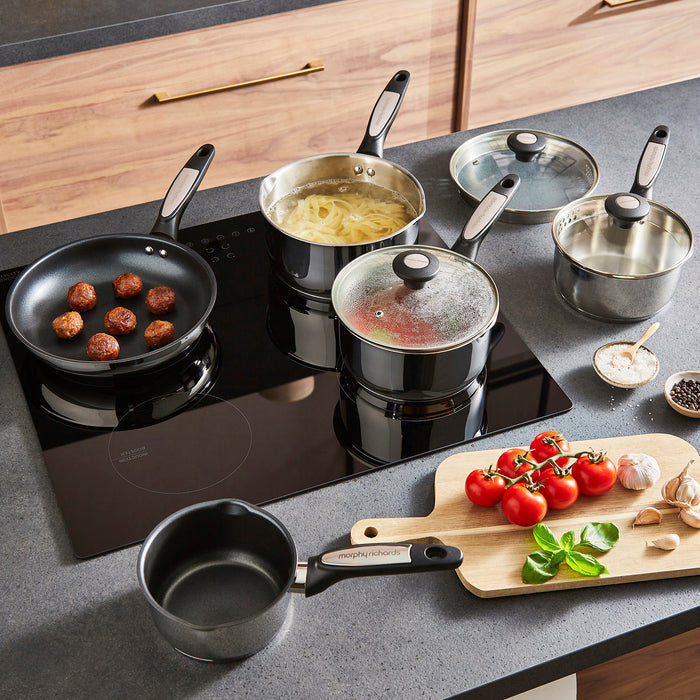 Cooking scene with pots, pans, and a cutting board on a kitchen counter.