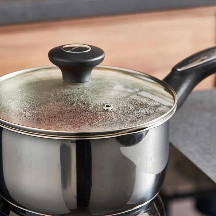Stainless steel pot with a black handle and lid on a wooden surface