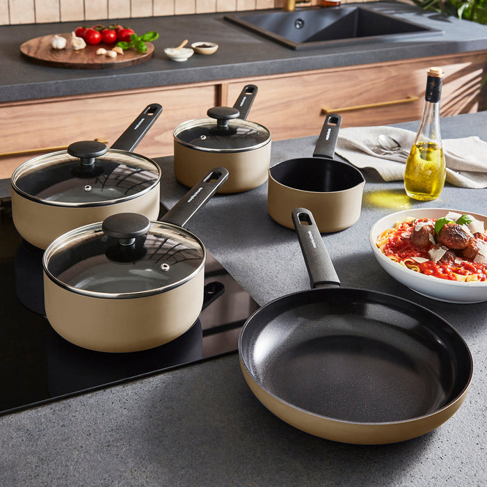 Set of cookware including pots, pans, and a bowl of pasta on a kitchen counter.