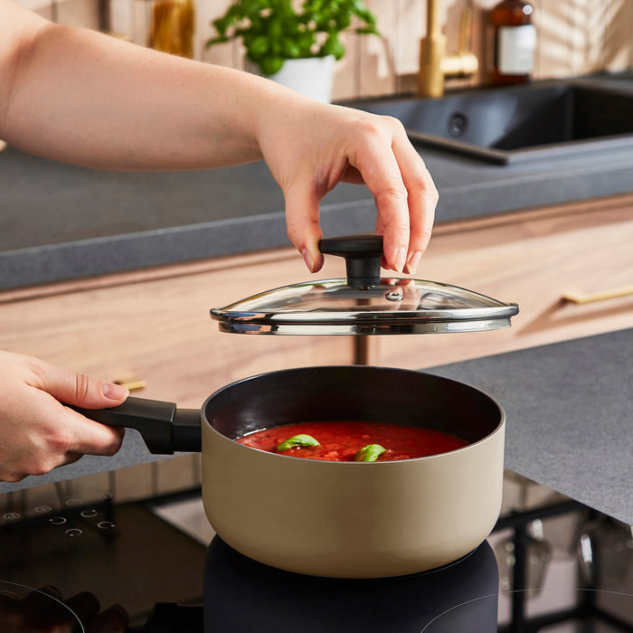 Person closing a pot lid on a stove with a kitchen in the background