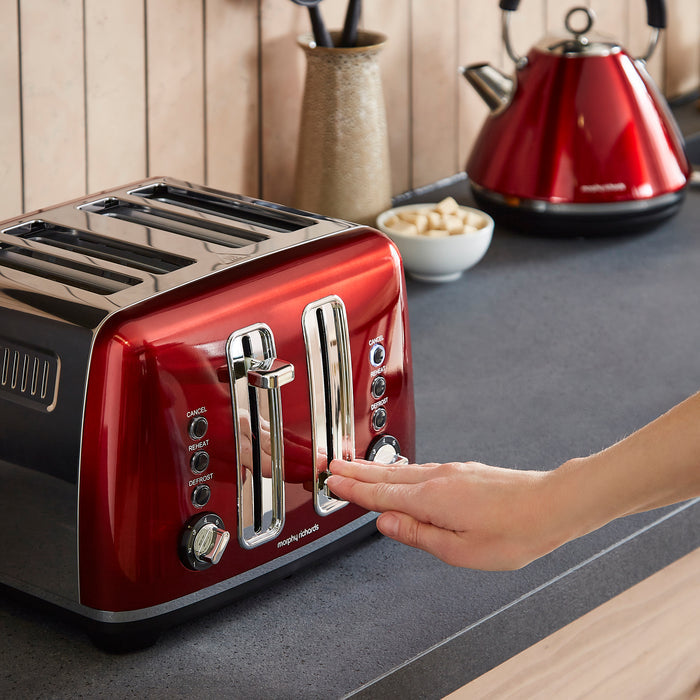 Red toaster with a hand pressing a button on a kitchen counter.