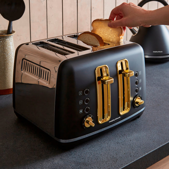 Black toaster with gold accents being used to toast bread on a kitchen counter.