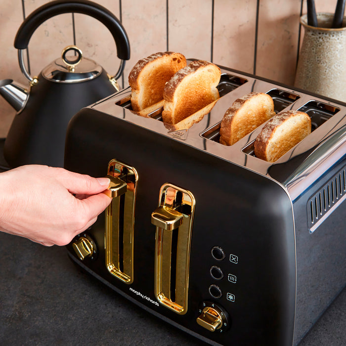 Black toaster with gold accents and four slices of toast, next to a black kettle.