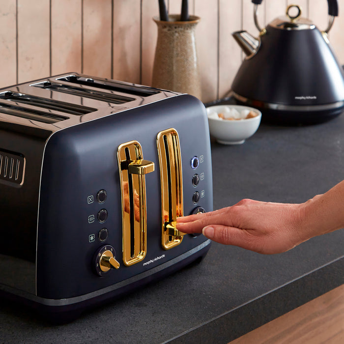 Blue toaster with gold accents on a kitchen counter, being operated by a hand.
