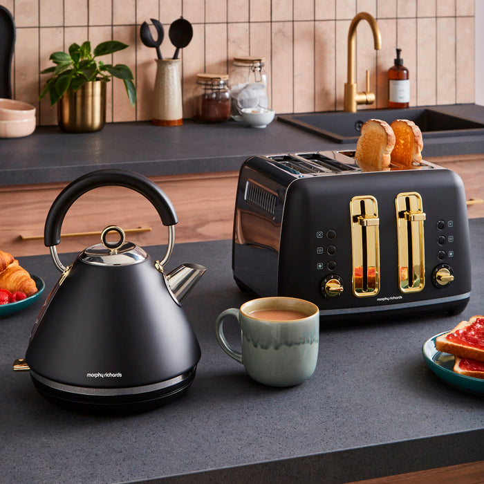 Black kettle and toaster on a kitchen counter with a cup of coffee and toast.