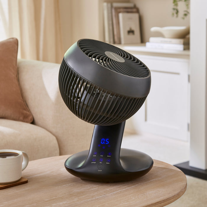 Black fan on a wooden table in a living room setting