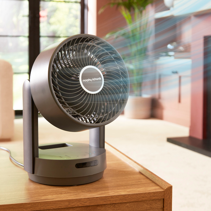 Portable fan on a wooden surface with a blurred indoor background