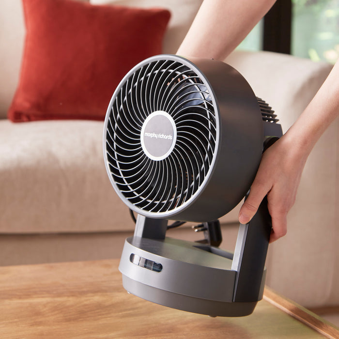 person moving desktop fan from living room