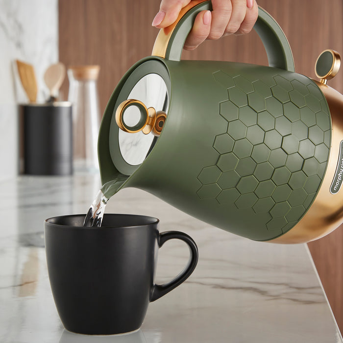 hand pouring water from a green kettle into a mug