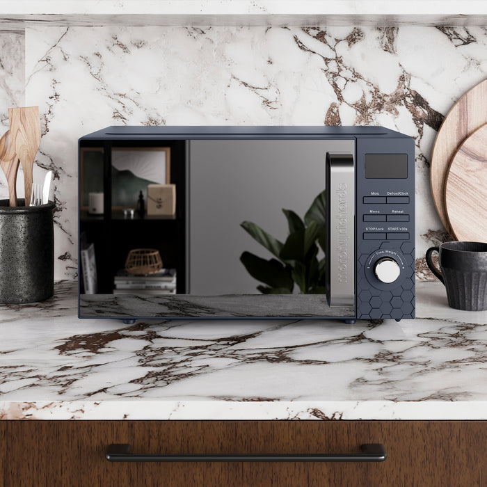 Navy microwave oven on a marble countertop with a kitchen setting.