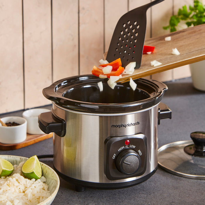 Morphy Richards slow cooker with food being added on a kitchen counter