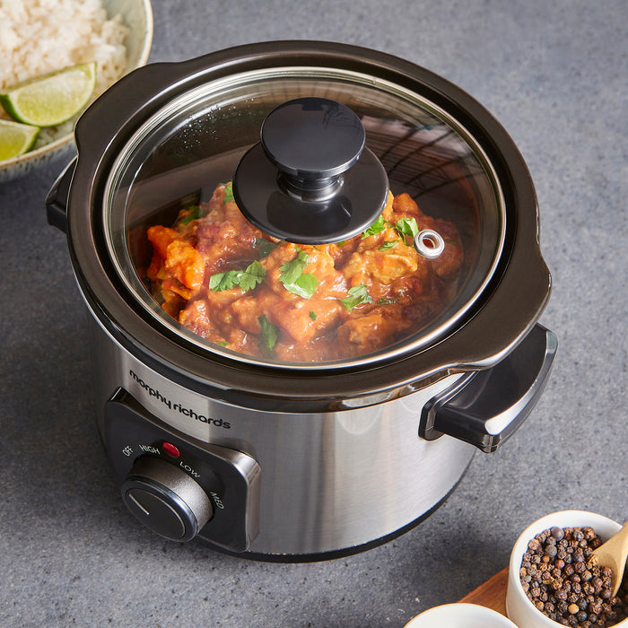 Slow cooker with food inside on a grey surface, featuring the brand 'Morphy Richards'.