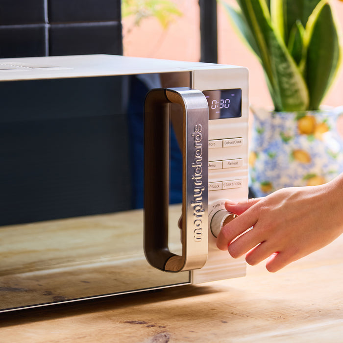 Person using a digital microwave oven on a kitchen counter with a plant in the background