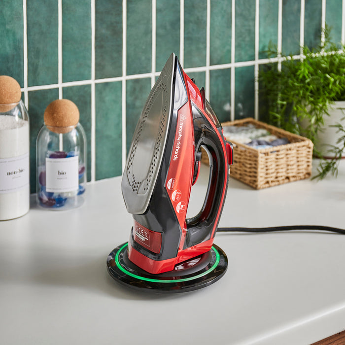 Red and black iron on a white surface with a green tiled wall in the background