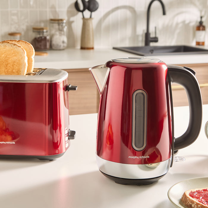 Red kettle and toaster set on a kitchen counter with toast and fruit.