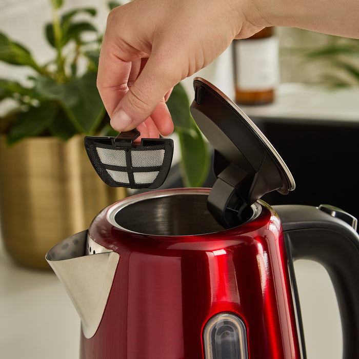 Red jug kettle with a hand placing a black filter into it.