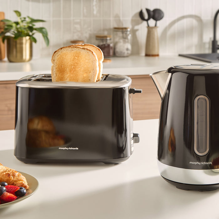 Black Morphy Richards toaster with a slice of toast and a kettle on a kitchen counter.