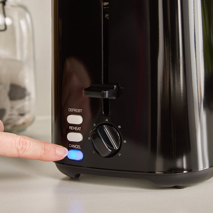 Person pressing a button on a black toaster with control knobs.