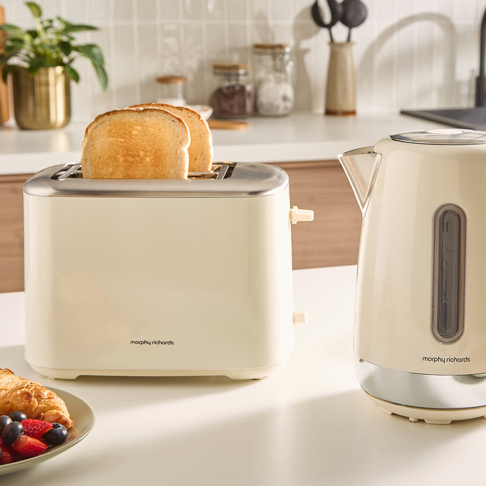 Beige toaster with a slice of toast and a kettle on a kitchen counter.