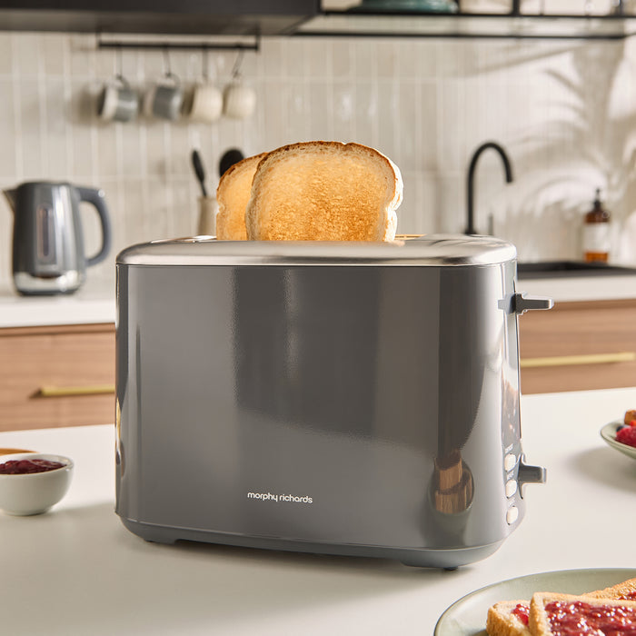 Grey toaster with a slice of toast on a kitchen counter