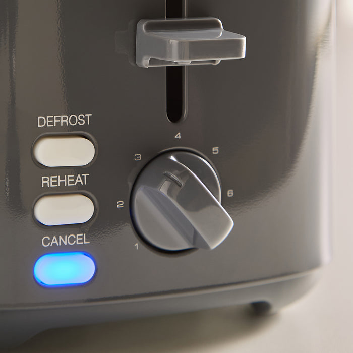 Control panel of a grey toaster with buttons labeled 'Defrost', 'Reheat', and 'Cancel'.