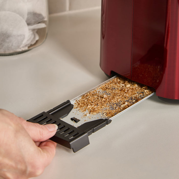 Person removing the crumb tray from a red toaster