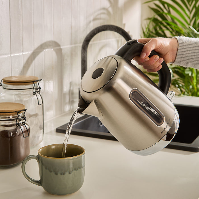 Kettle pouring boiling water into a mug