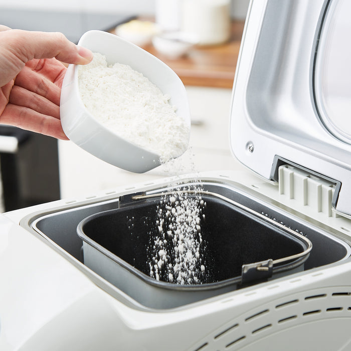 flour being poured into a breadmaker