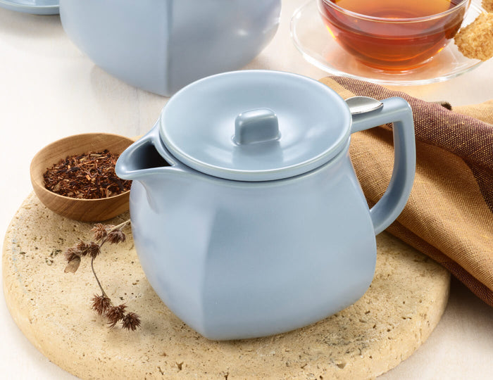 MAIN PDP | Fiore Stone Blue Teapot with lid on table with loose tea and teacup