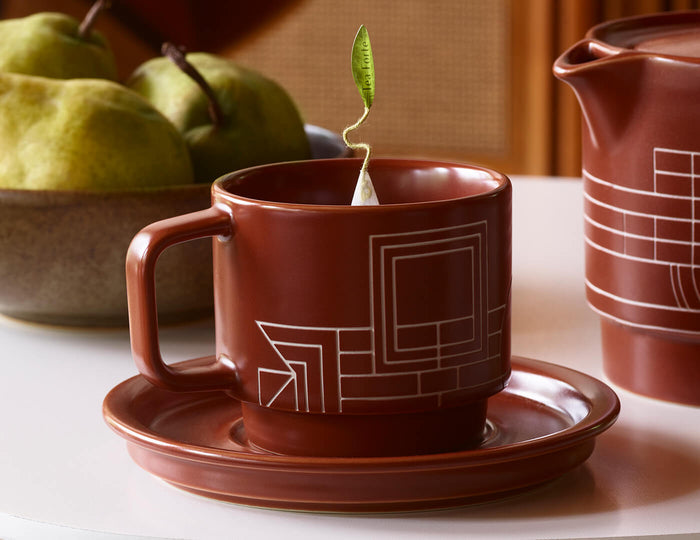 MAIN PDP | Terra stoneware teacup and saucer with a pyramid infuser inside on a table with pears