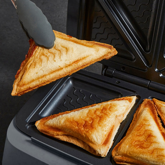 Toasted sandwich being removed from a sandwich maker with a hand wearing a black glove.