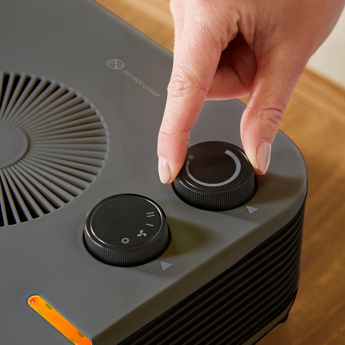 Hand adjusting heater on a with a wooden surface background