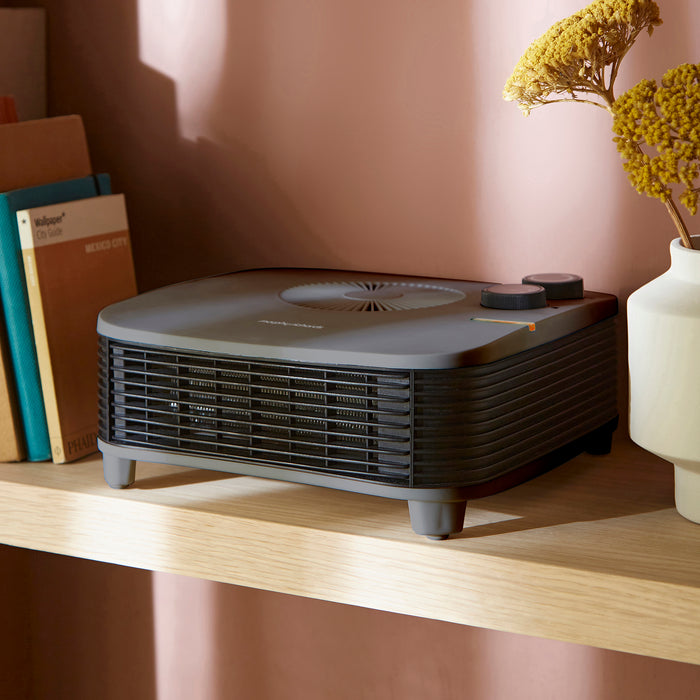 Portable heater on a shelf with books and a plant in the background