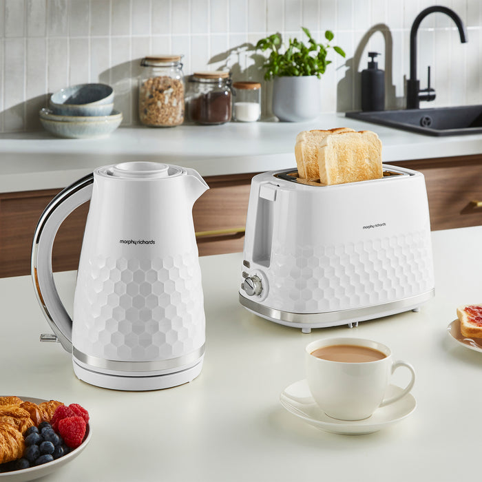 White electric kettle and toaster on a kitchen counter with a cup of coffee and breakfast items.