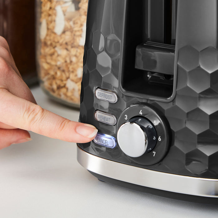 Person pressing a button on a modern toaster with a geometric design.