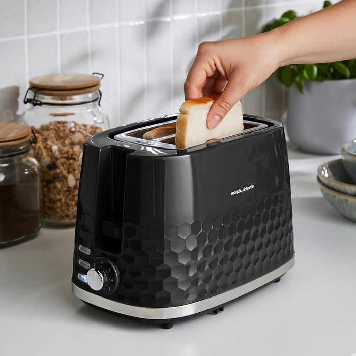 Black toaster with a person placing bread inside, set against a kitchen background.