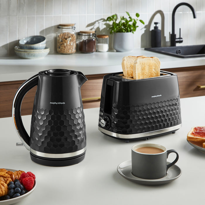 Black kettle and toaster on a kitchen counter with a cup of coffee and breakfast items.