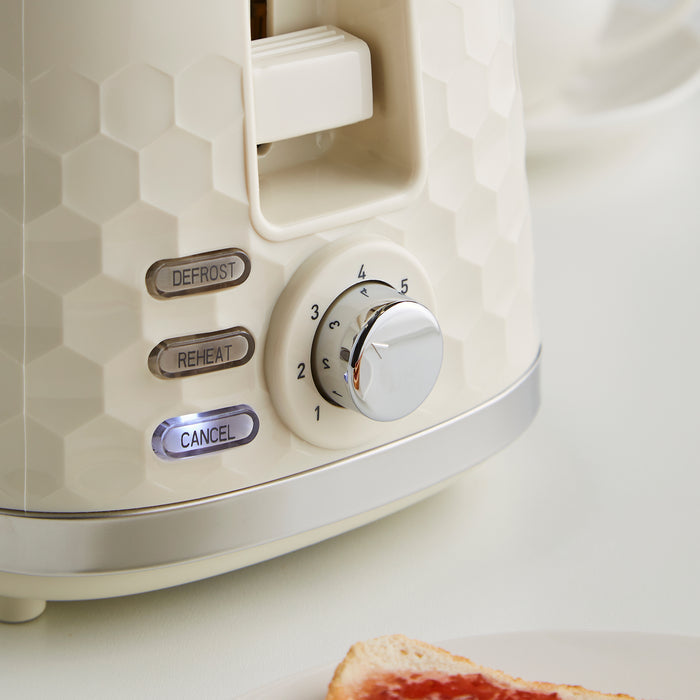 Close-up of a cream toaster with control knobs on a white background